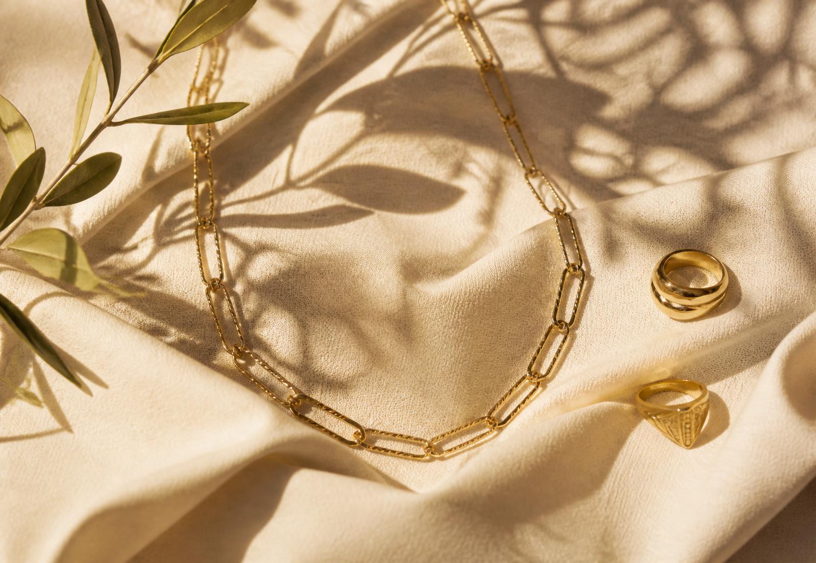 Colar e anéis banhados a ouro 18k sobre linho cru com ramo de oliveira